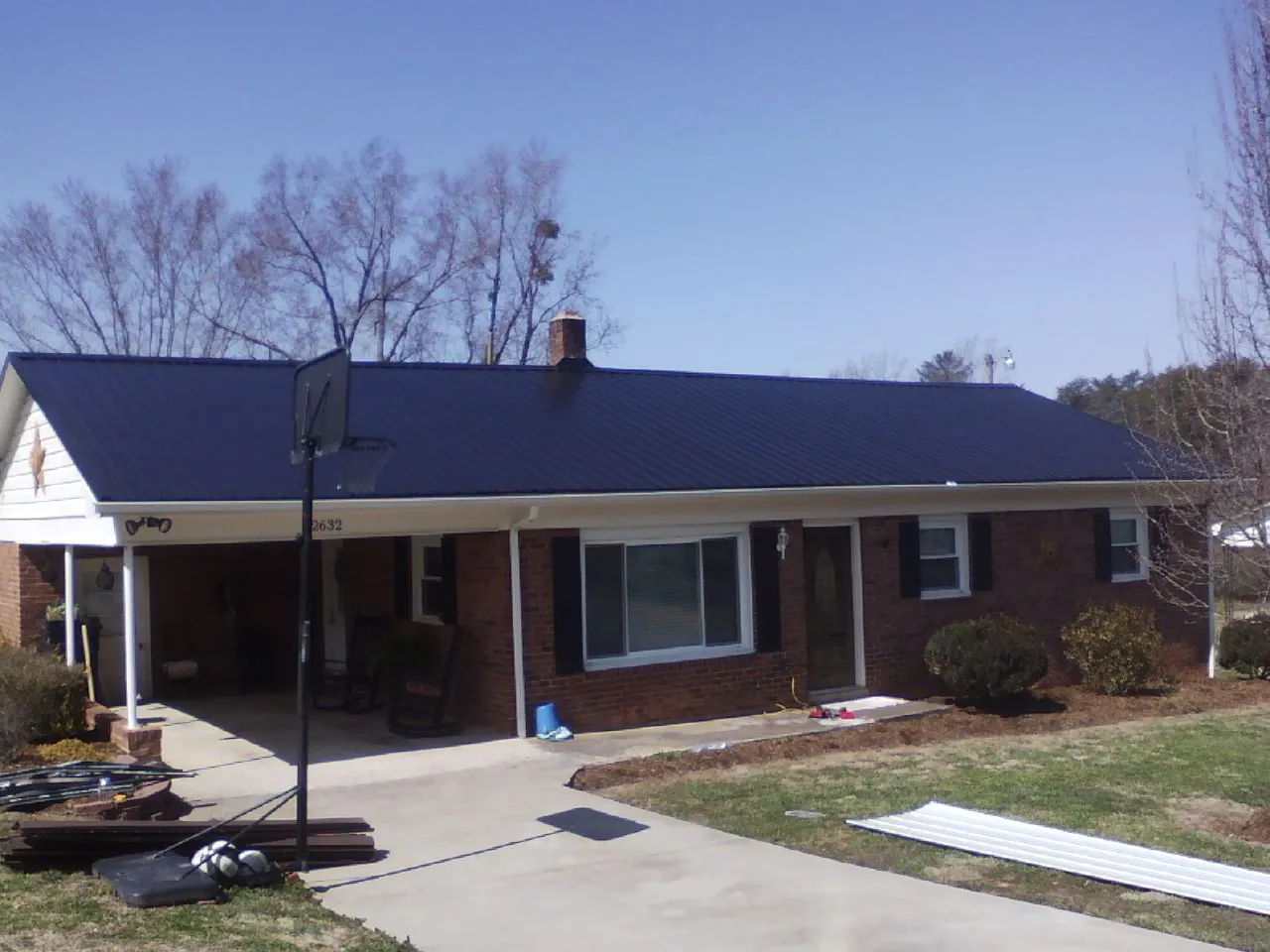 Finished dark blue metal roof on a brick ranch with a carport in Rancocas