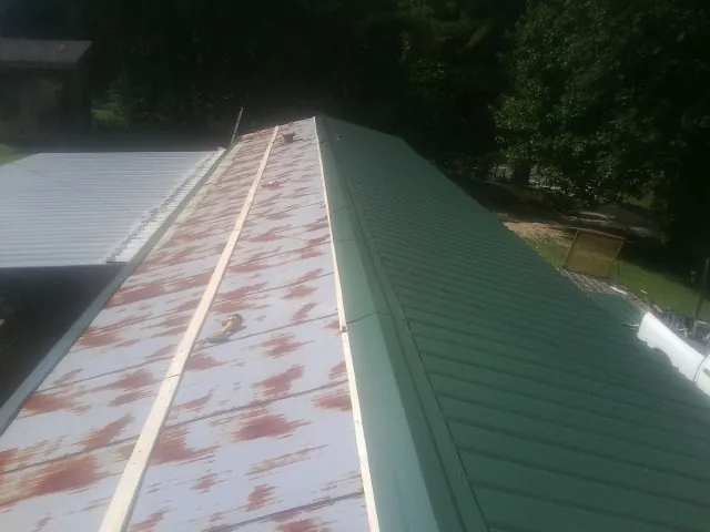 Old rusted panels beside newly installed green metal roofing — Wind Damage Roof Repair by Roofing Brothers in Rancocas