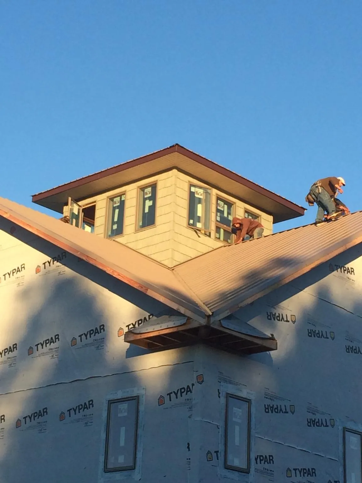 Roofers working around a rooftop cupola on a new metal roof at sunset — Roof Waterproofing in Rancocas by Roofing Brothers